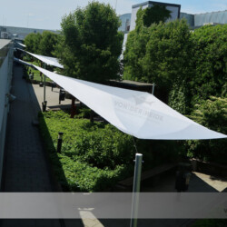 Aufrollbare Sonnensegel für Aufenthaltsbereich eines Gewerbebetriebes. Drei große aufrollbare Sonnensegel Soliday-C für Aufenthaltsbereich im Außenbereich eines Gewerbebetriebes.