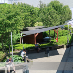 Sonnensegel für Mitarbeiter einer Firma Drei große aufrollbare Sonnensegel Soliday-C für Aufenthaltsbereich im Außenbereich eines Gewerbebetriebes.