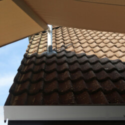 Detail einer Dachmontage Ein Mast wurde durch eine Öffnung über das Dach geführt und an der Giebelwand montiert. Der Klempner oder Dachdecker dichtet den Mast-Dachanschluss ab. Individuelle Lösung mit Sonnensegel. Winsen an der Luhe