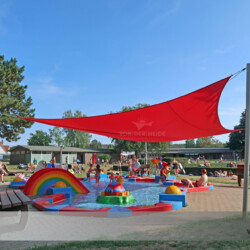 Freizeitbad Lübeck-Schlutup-manuelles Rollup-Sonnensegel Soliday M Rotes aufrollbares Sonnensegel über Planschbecken im Freizeitbad Schlutup in Lübeck