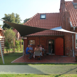 Hypar-Segel auf dem Land Hypar-Saisonsegel an Ziegelhaus auf dem Land. Sonnen- und Regenschutz.