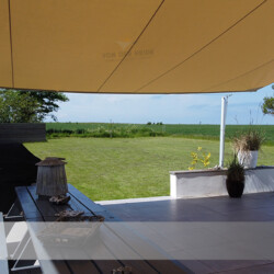 Unter einem Markisen-Segel Blick in Garten und Felder von einer Terrasse mit Markisen-Sonnensegel