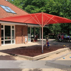 Sonnenschirm May-Schattello in Sandkiste Roter Sonnenschirm May-Schattello 6x4m mit PVC-Bespannung in einer Sandkiste eines Kindergartens