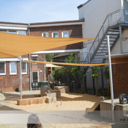 Kita-Segel mit Kubus-Befestigung aus Robinienholz Aufrollbare Sonnensegel in einer Kita mit Mastbefestigungen in Kuben aus Robinienholz.