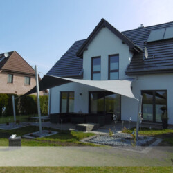 Fünfeck-Segel an Wohnhaus Festverspanntes Saisonsegel mit zwei Wandbefestigungen und drei Masten.