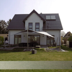 Hypar-Sonnensegel Festverspanntes Saisonsegel mit zwei Wandbefestigungen und drei Masten.