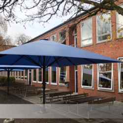 Schutz für Schüler und Lehrer durch die Stadt Kiel Vier Profi-Großschirme als Sonnen- und Regenschutz über Sitzplätzen auf Schulhof.