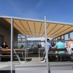 Sunrain Leiner-Falt-Pergola in Berlin. Seitenansicht Wind- und regenfeste Falt-Pergola Leiner Sun and Rain auf einer Dachterrasse eines Gewerbeobjektes in Berlin.